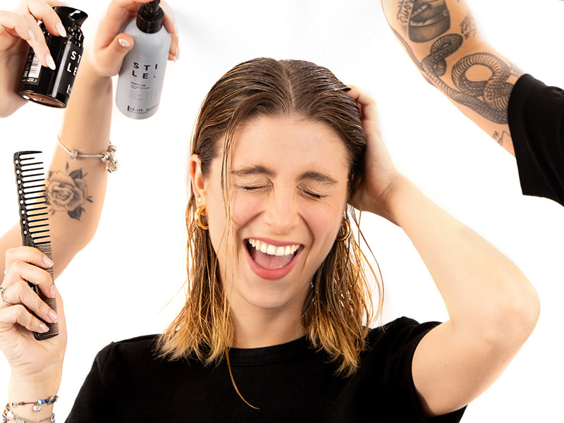 I segreti per una piega perfetta: donna sorridente con capelli bagnati, prodotti per capelli Stile e pettine. Tutorial per piega perfetta.