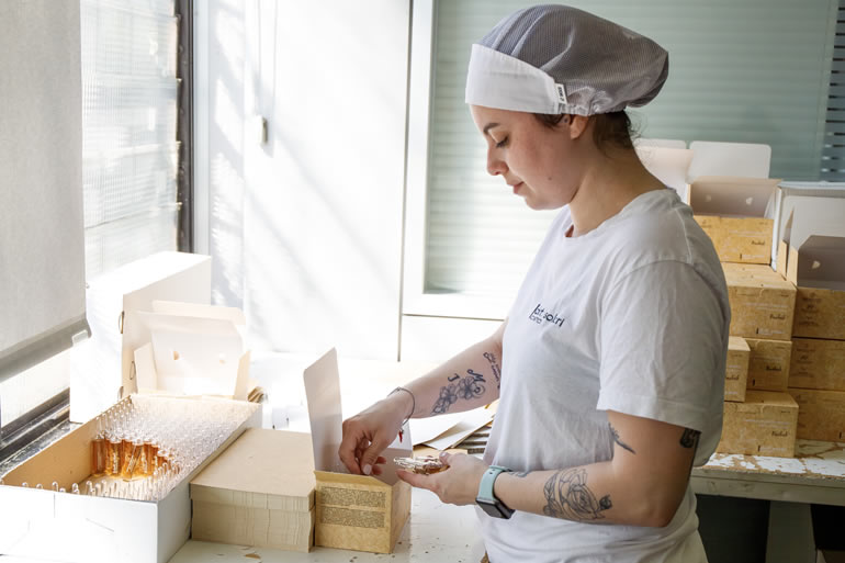 Dott. Solari Dana Staff: Donna confeziona prodotti artigianali. Team al lavoro per la qualità. Dettaglio e cura nei prodotti.